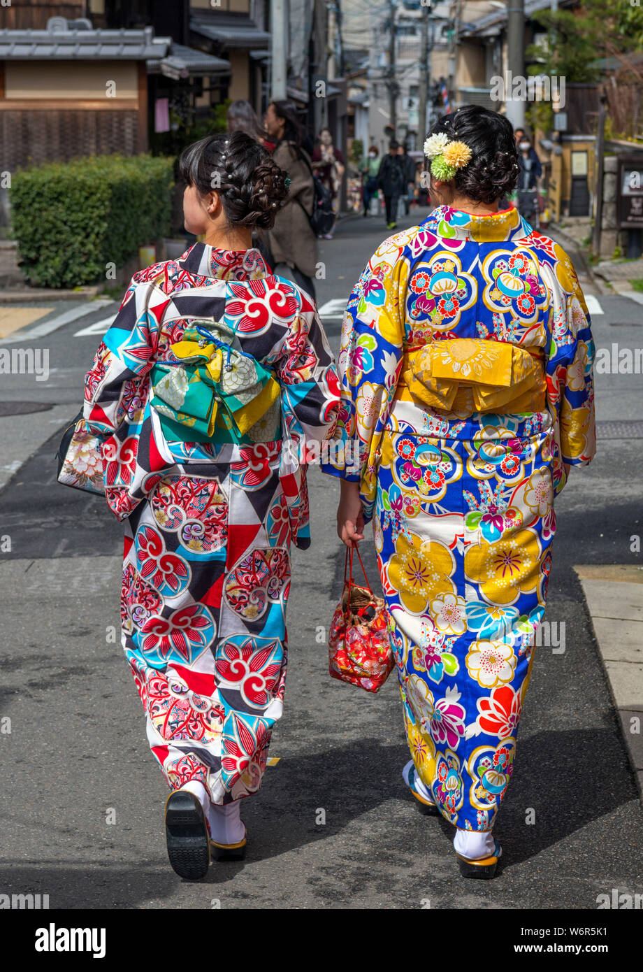 两位身着传统和服的女子走在京都历史悠久的祗园区街道上,非常适合拍摄真实的照片。