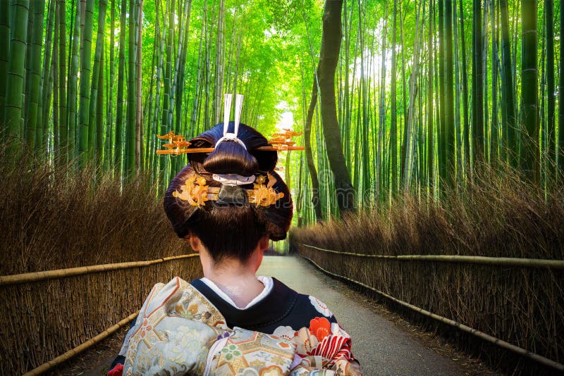 身着传统和服的女子走过京都宁静的岚山竹林,展现宁静的自然体验
